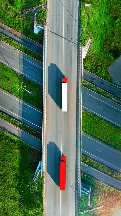Truck logistic aerial. Two trucks motion by the highway intersection road between fields. View from drone.; Shutterstock ID 1503846644; purchase_order: -; job: -; client: -; other: -